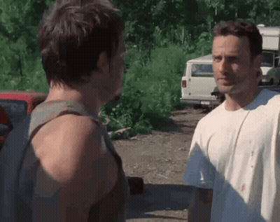 Two Men Are Standing Next To Each Other In A Parking Lot And Talking . GIF
