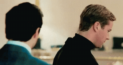Two Men Are Standing Next To Each Other In A Room And Looking At Each Other . GIF
