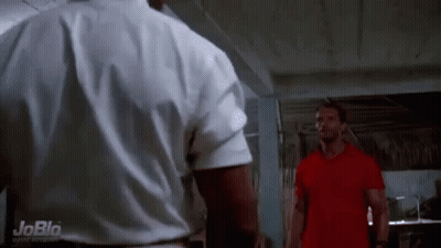 Two Men Are Standing Next To Each Other In A Room . One Of The Men Is Wearing A Red Shirt . GIF