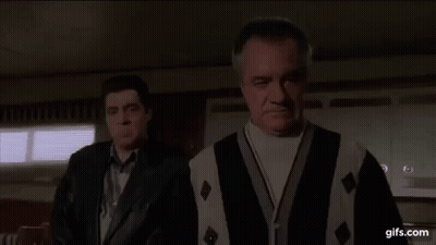 Two Men Are Standing Next To Each Other In A Room . One Of The Men Is Wearing A Sweater And A Leather Jacket . GIF