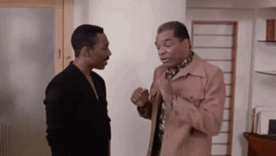 Two Men Are Standing Next To Each Other In A Room Talking To Each Other . GIF