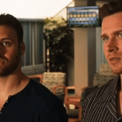 Two Men Are Standing Next To Each Other In A Room With A Tv On The Wall GIF