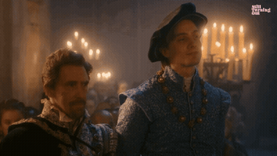 Two Men Are Standing Next To Each Other In A Room With Candles And The Words Still Burning On The Bottom Left GIF