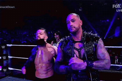 Two Men Are Standing Next To Each Other In A Wrestling Ring . One Of The Men Has A Beard . GIF