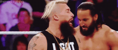 Two Men Are Standing Next To Each Other In A Wrestling Ring . One Of The Men Has A Beard . GIF