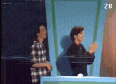 Two Men Are Standing Next To Each Other In Front Of A Blue Wall . GIF
