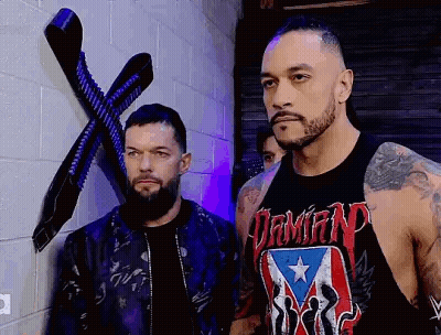 Two Men Are Standing Next To Each Other In Front Of A Brick Wall In A Room . GIF