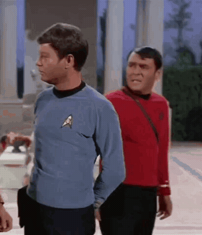 Two Men Are Standing Next To Each Other In Front Of A Building . GIF