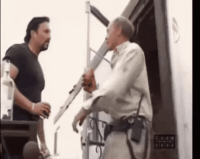 Two Men Are Standing Next To Each Other In Front Of A Building . GIF
