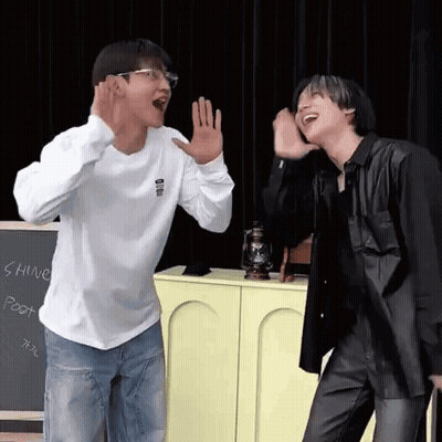 Two Men Are Standing Next To Each Other In Front Of A Chalkboard . GIF