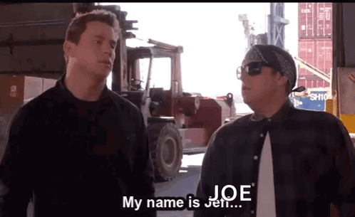 Two Men Are Standing Next To Each Other In Front Of A Forklift And One Of Them Is Saying His Name Is Joe . GIF