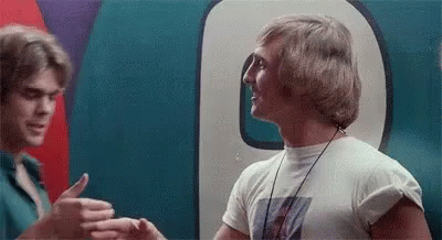 Two Men Are Standing Next To Each Other In Front Of A Large Number 9 . GIF