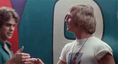 Two Men Are Standing Next To Each Other In Front Of A Large Number 9 . GIF