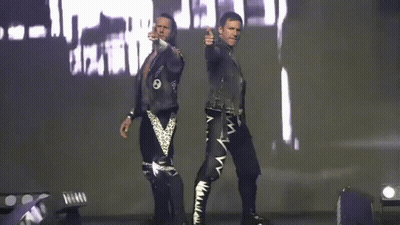 Two Men Are Standing Next To Each Other In Front Of A Large Screen With The Word Death On It GIF