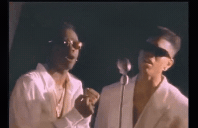 Two Men Are Standing Next To Each Other In Front Of A Microphone And Singing Into It . GIF