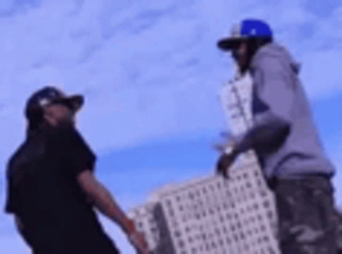 Two Men Are Standing Next To Each Other In Front Of A Tall Building . GIF