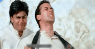 Two Men Are Standing Next To Each Other On A Beach . One Of The Men Is Holding A Gun . GIF