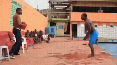 two men are standing next to each other on a concrete surface in front of a pool .