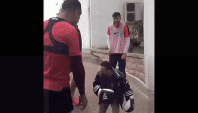 Two Men Are Standing Next To Each Other On A Sidewalk . GIF