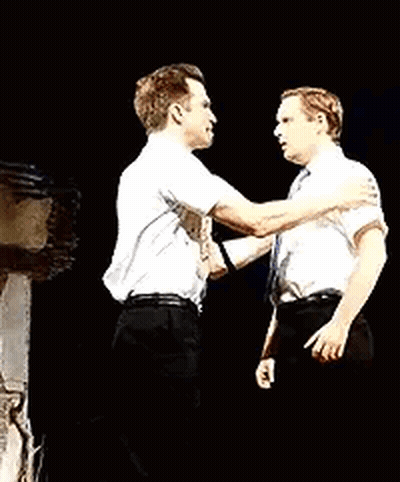 Two Men Are Standing Next To Each Other On A Stage And Hugging Each Other . GIF