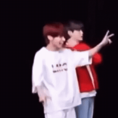 Two Men Are Standing Next To Each Other On A Stage And One Of Them Is Giving The Peace Sign . GIF