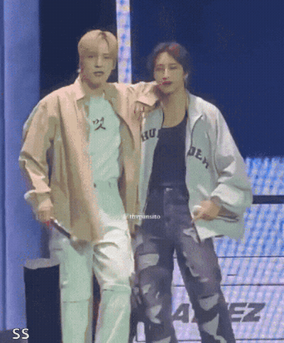 Two Men Are Standing Next To Each Other On A Stage And One Of Them Is Holding A Microphone . GIF