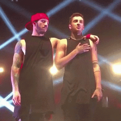 Two Men Are Standing Next To Each Other On A Stage And One Of Them Is Hugging The Other . GIF