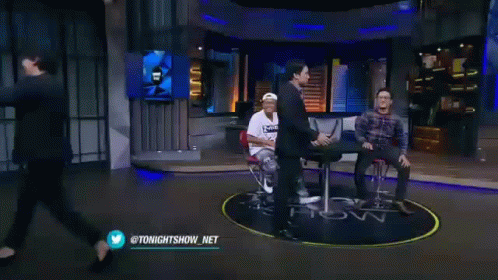 Two Men Are Standing Next To Each Other On A Stage . GIF