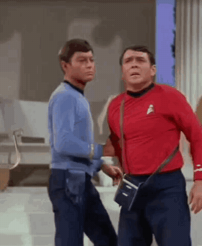 Two Men Are Standing Next To Each Other On A Stage . One Of The Men Is Wearing A Red Shirt . GIF