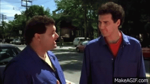 Two Men Are Standing Next To Each Other On A Street And Talking To Each Other . GIF