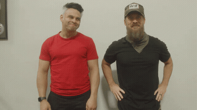 Two Men Are Standing Next To Each Other One Wearing A Hat That Says Hap GIF