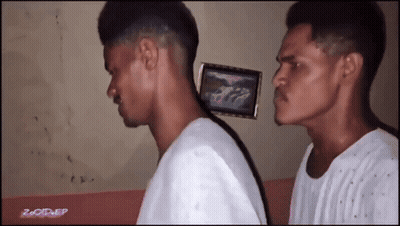 Two Men Are Standing Next To Each Other With A Picture Of A Car On The Wall Behind Them GIF