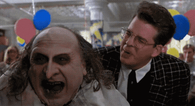 Two Men Are Standing Next To Each Other With Balloons Hanging From The Ceiling In The Background GIF