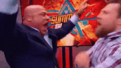 Two Men Are Standing Next To Each Other With Their Arms In The Air In Front Of A Poster . GIF