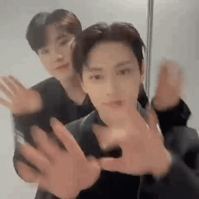 Two Men Are Standing Next To Each Other With Their Hands Outstretched . GIF