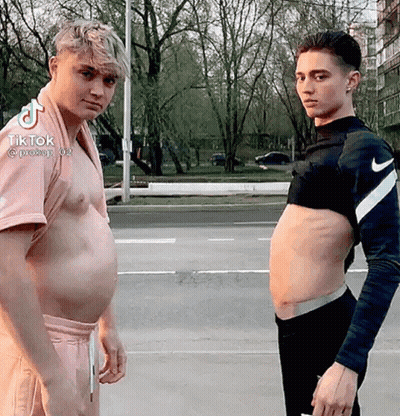 Two Men Are Standing Next To Each Other With Their Stomachs Exposed . GIF