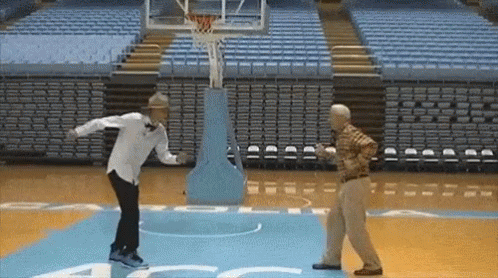 Two Men Are Standing On A Basketball Court With A Basketball Hoop In The Background .. GIF