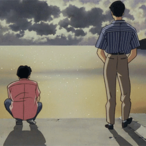 Two Men Are Standing On A Beach Looking At The Water GIF