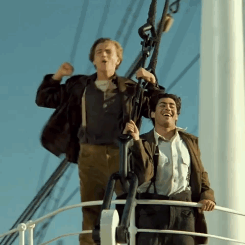 Two Men Are Standing On A Boat Laughing And Raising Their Arms In The Air GIF