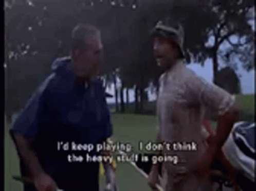 Two Men Are Standing On A Golf Course Talking To Each Other GIF