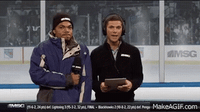 Two Men Are Standing On A Hockey Rink Talking Into Microphones . GIF