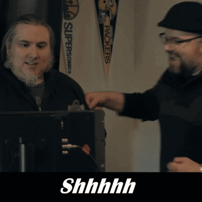 two men are talking in front of a sign that says " packers "