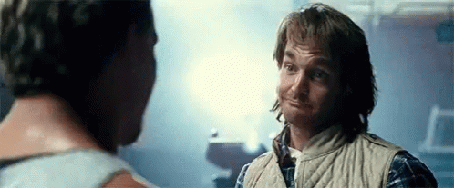 Two Men Are Talking To Each Other In A Dark Room . GIF