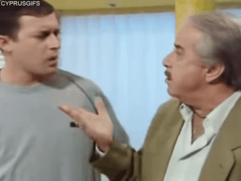 Two Men Are Talking To Each Other In A Room . One Of The Men Is Wearing A Suit . GIF
