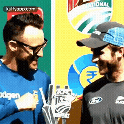 Two Men Are Talking To Each Other In Front Of A Sign That Says National GIF