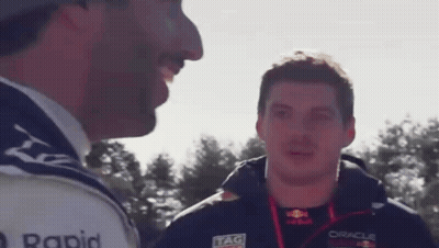 Two Men Are Talking To Each Other In Front Of Trees . GIF