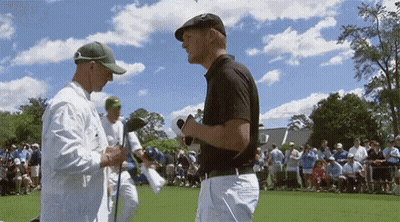 Two Men Are Talking To Each Other On A Golf Course GIF