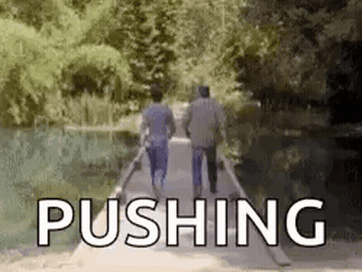 Two Men Are Walking Across A Bridge With The Word Pushing In The Background . GIF