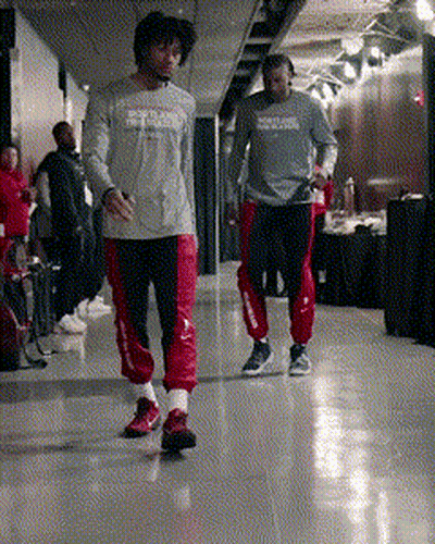 Two Men Are Walking Down A Hallway And One Has A Shirt That Says Reebok On It GIF