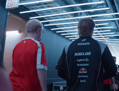 Two Men Are Walking Down A Hallway And One Of Them Is Wearing An Aleksib Navi.gg Jacket GIF